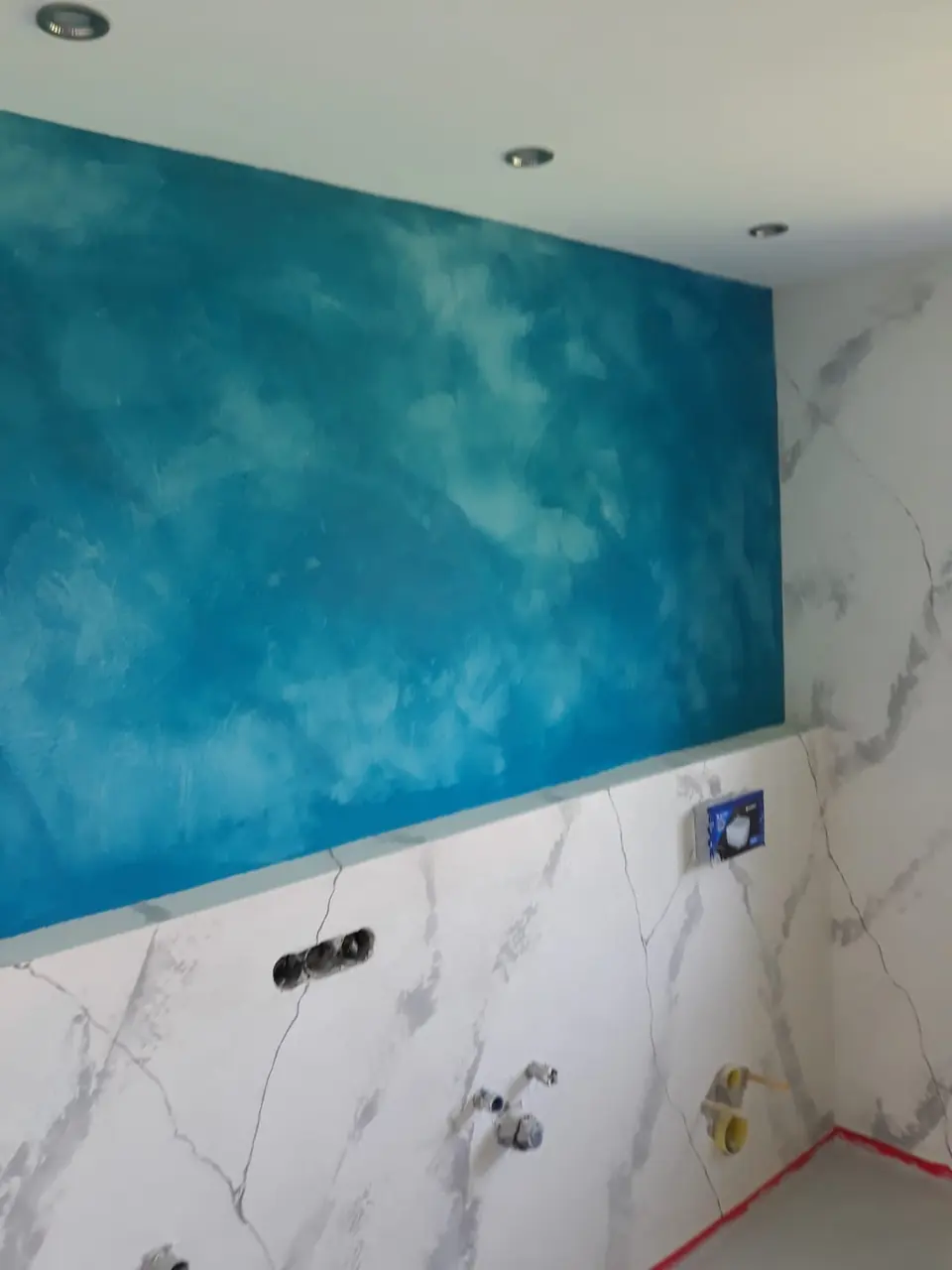 Badwand mit blauer Spachteltechnik über Marmoroptik