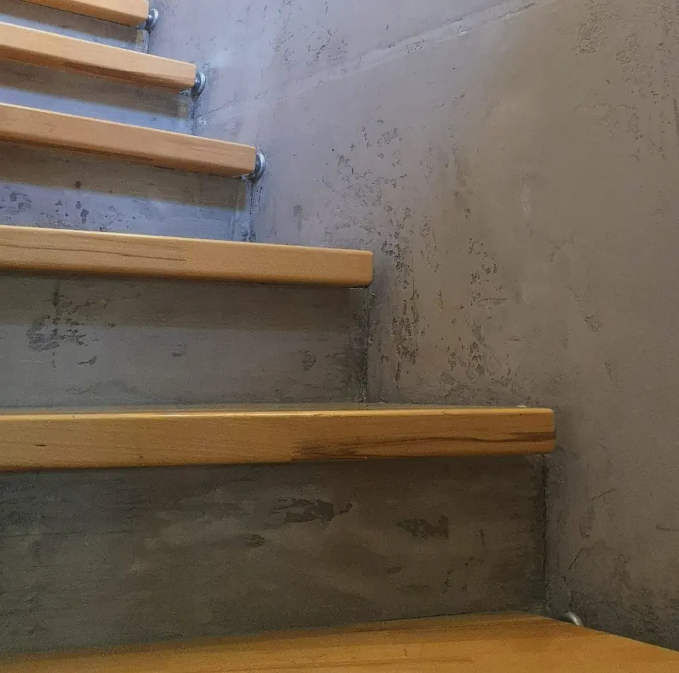 Holztreppe vor Wand in Betonoptik